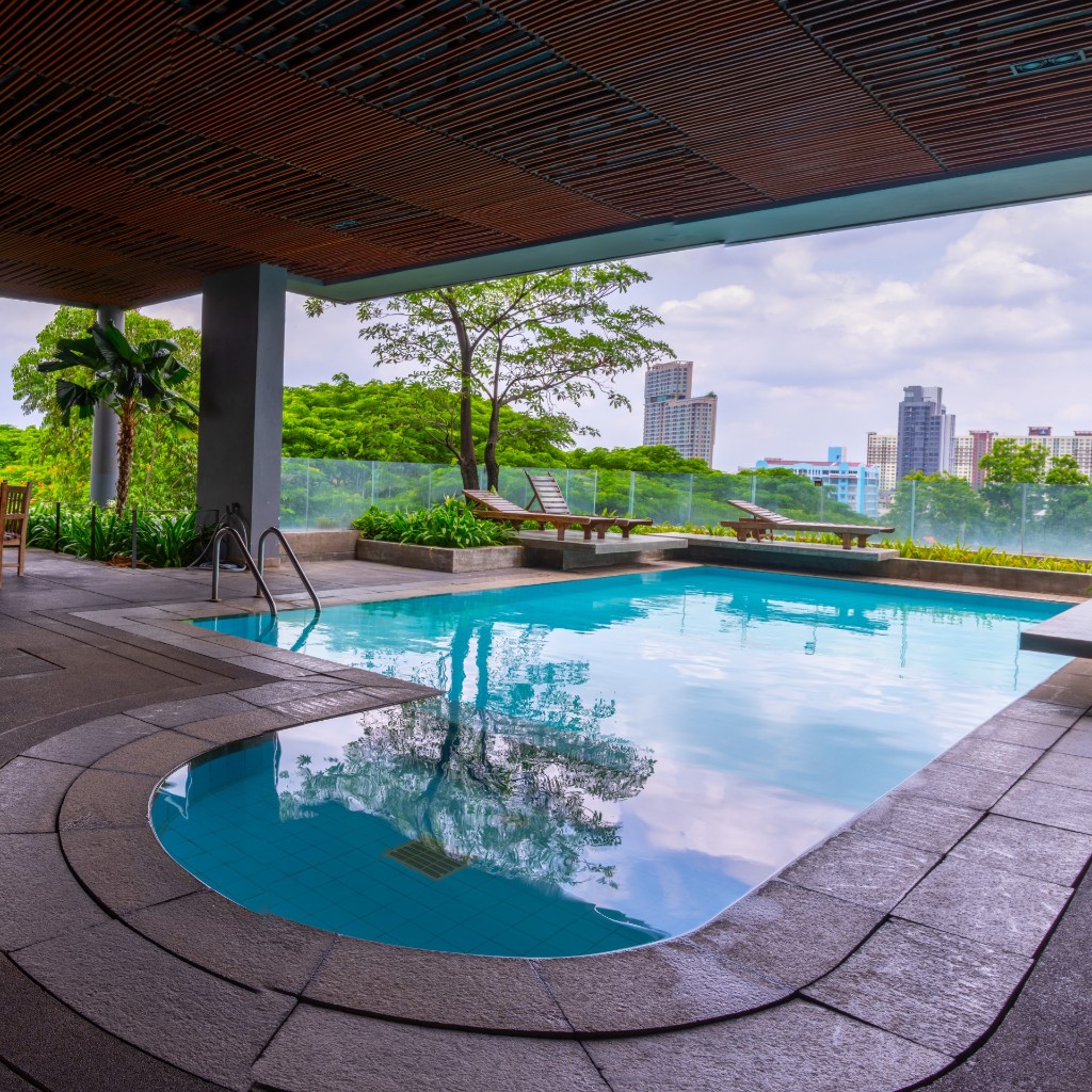 Rooftop swimming pool with wooden lounge chairs and city skyline